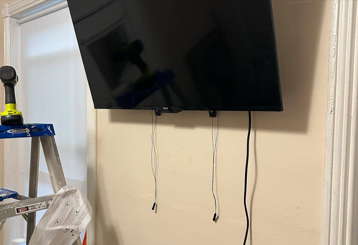 TV being mounted on wall with professional tools